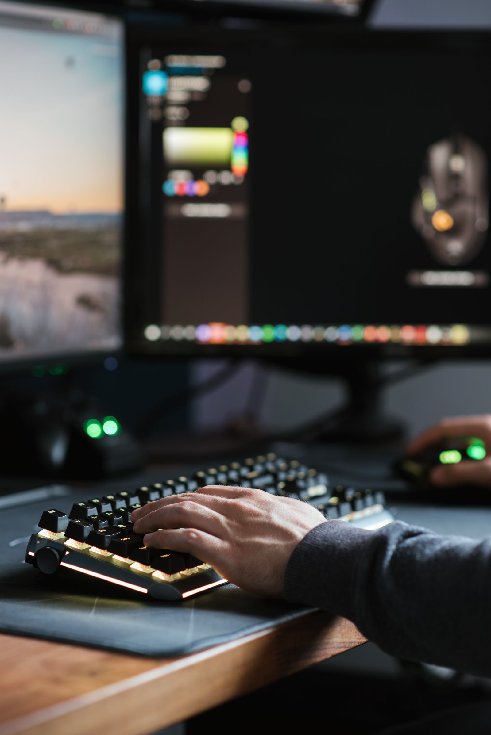Hands working at a keyboard in a multi-monitor computer workspace