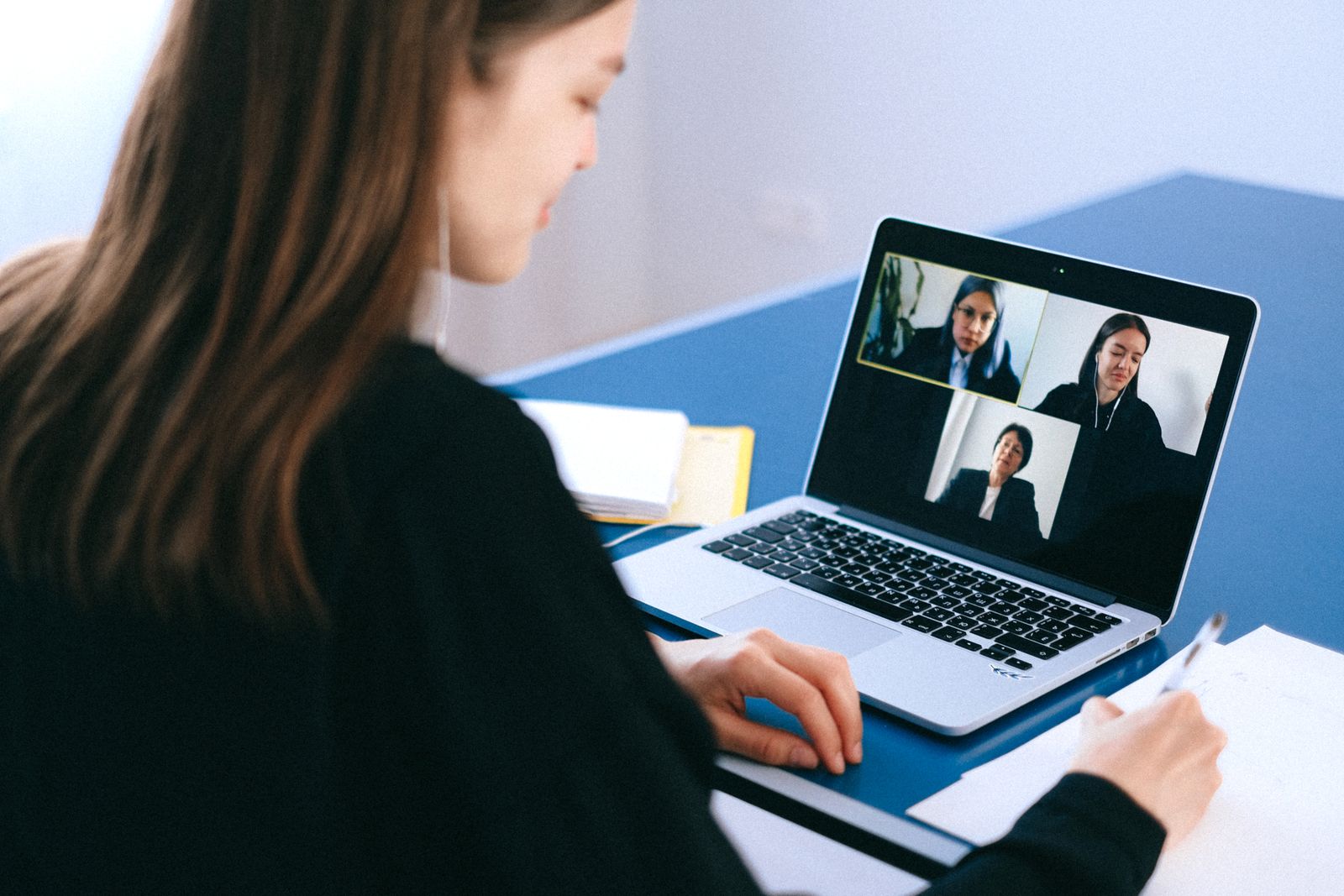 A person joining a group video call on a laptop at a table