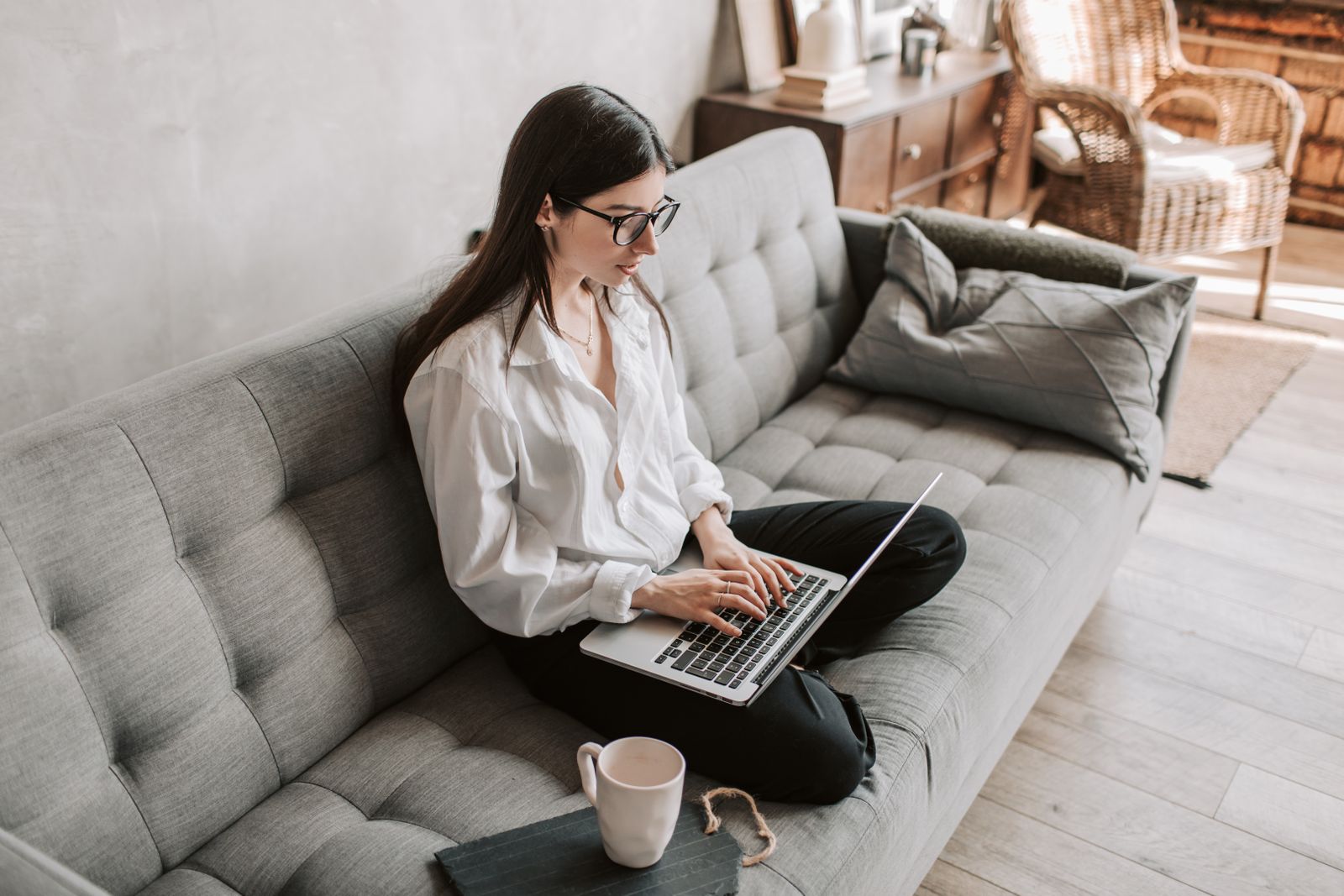 A woman using a laptop while sitting on a sofa at home