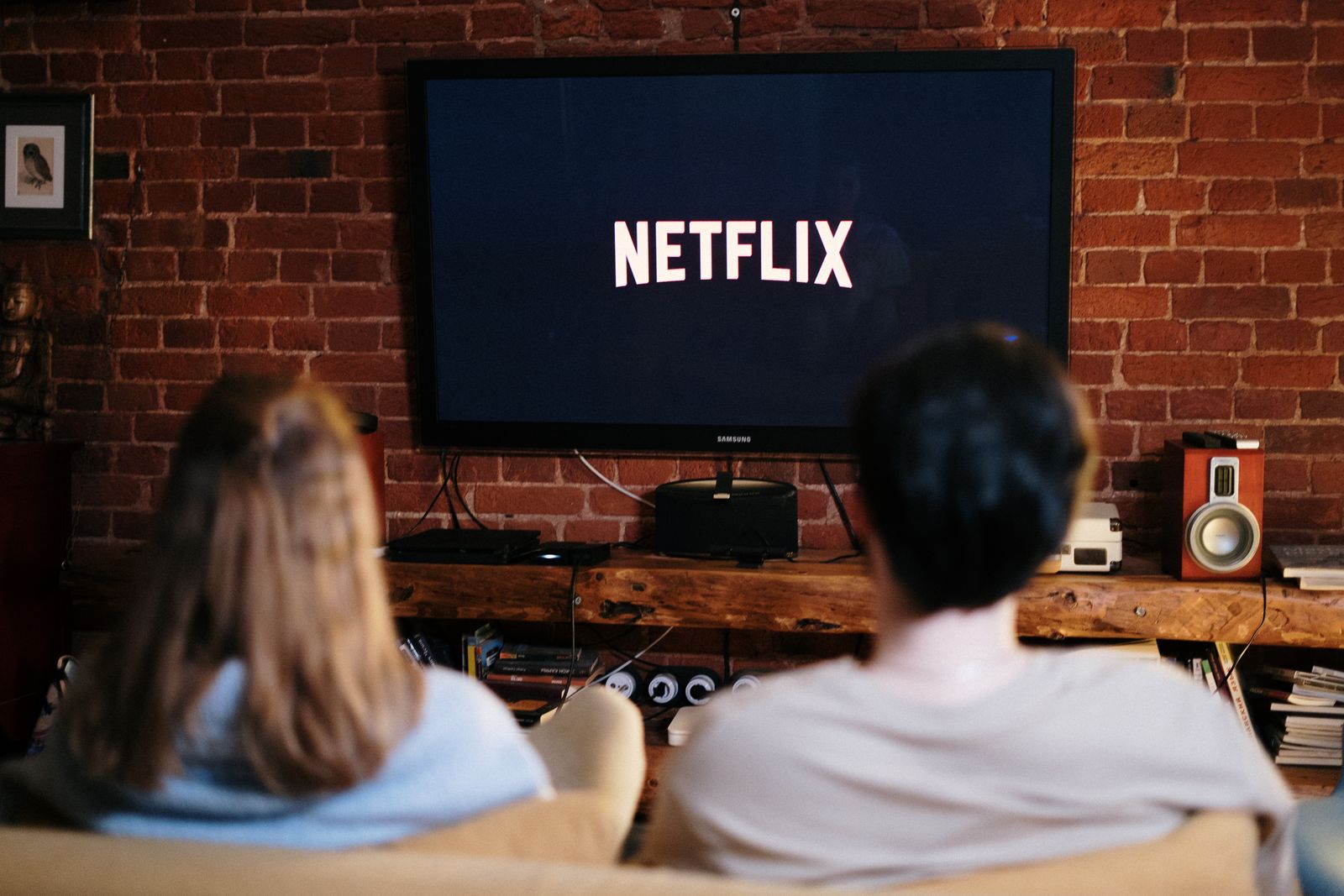 Two people watching a television together in a brick-walled living room