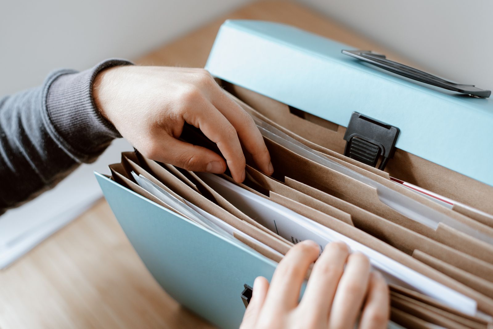 Hands arranging paper documents inside a home filing box