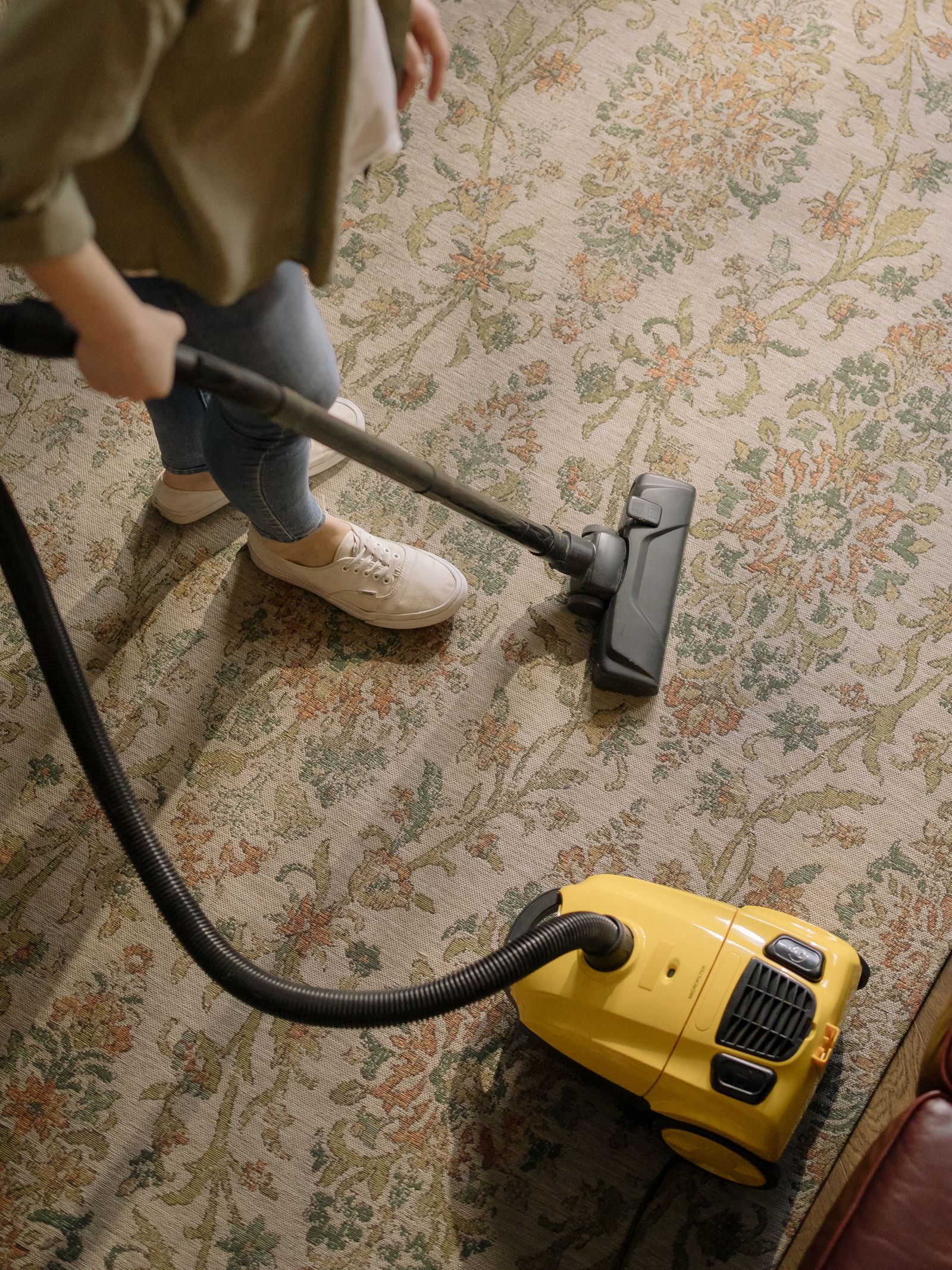 A person vacuuming a patterned rug at home