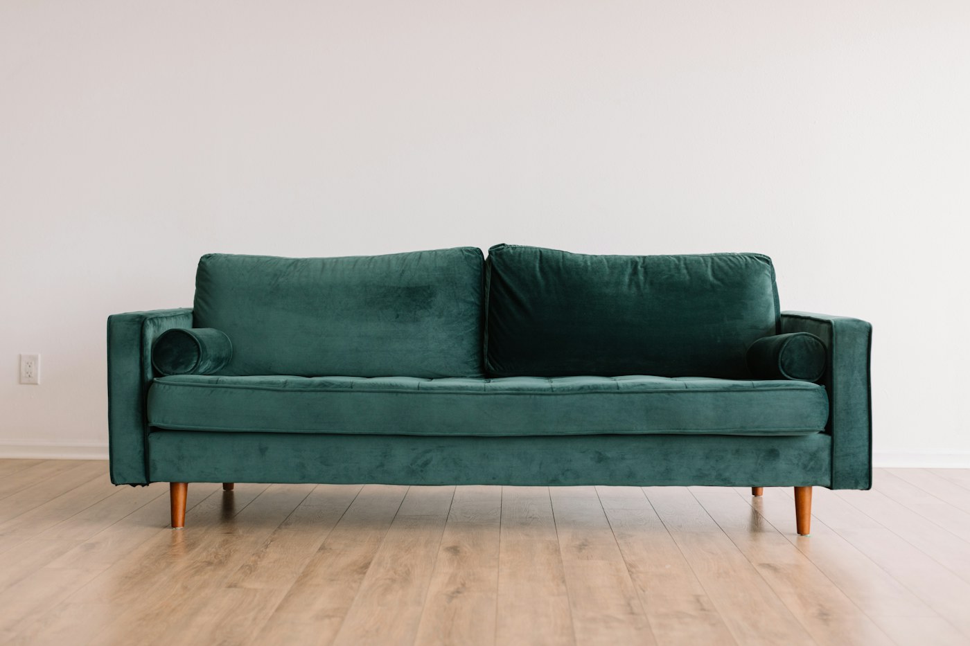 A compact living room with a green sofa and clear floor space