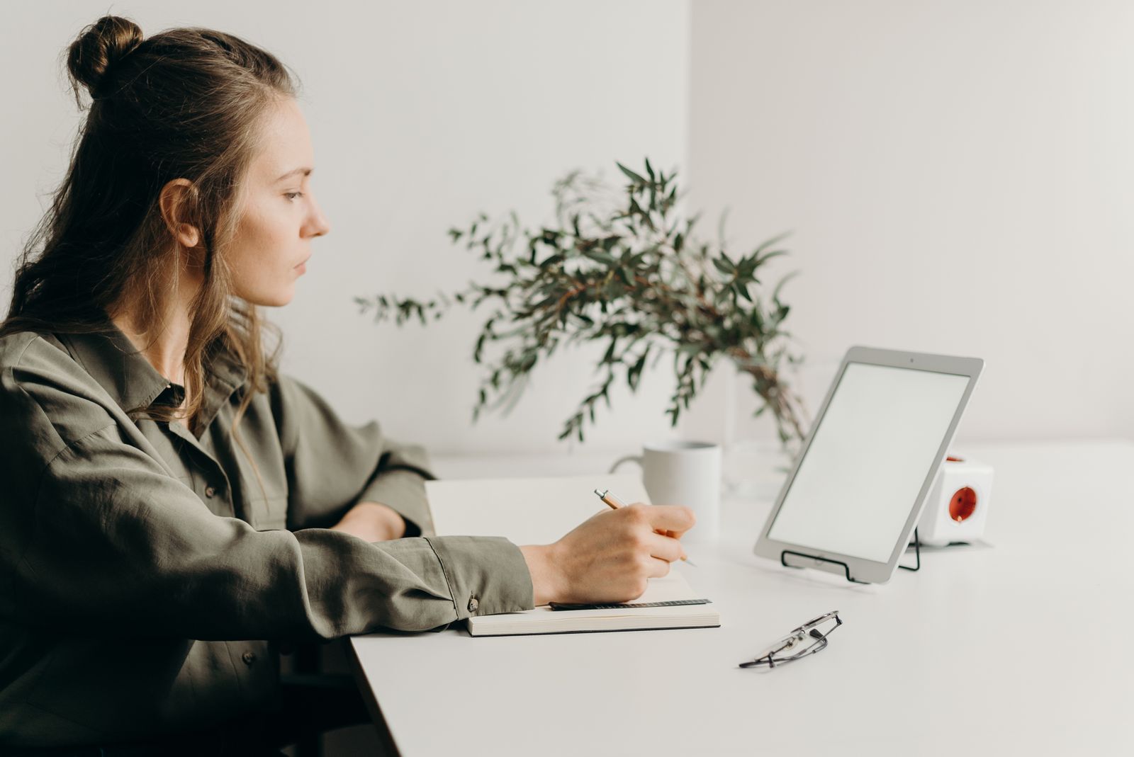 A woman using a laptop at a bright home desk