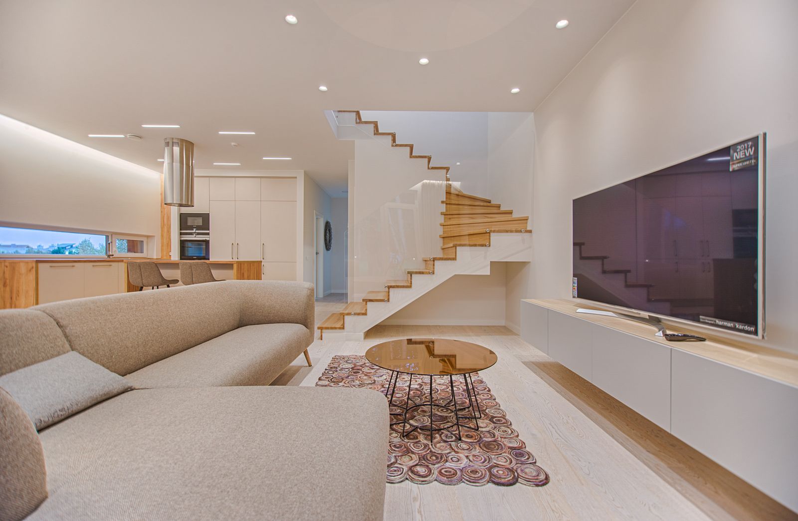 A large wall-mounted television beside the staircase in a living room
