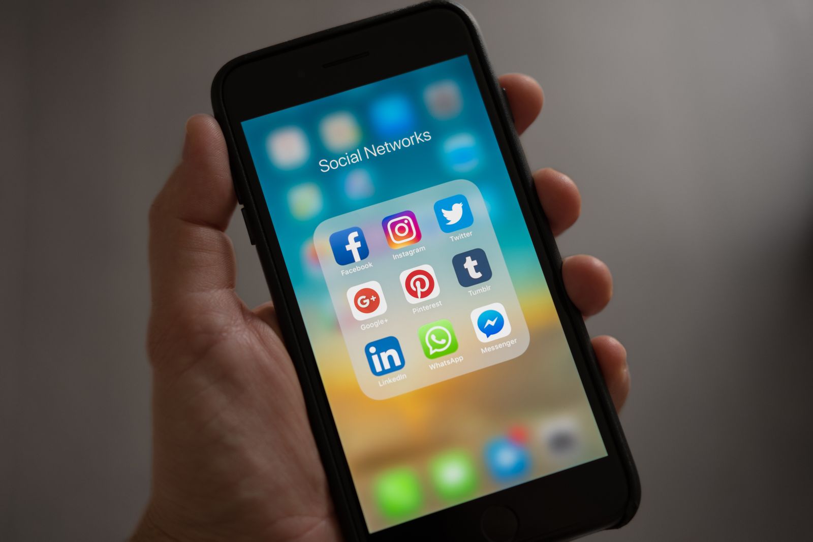 A hand holding a smartphone with apps visible on the screen