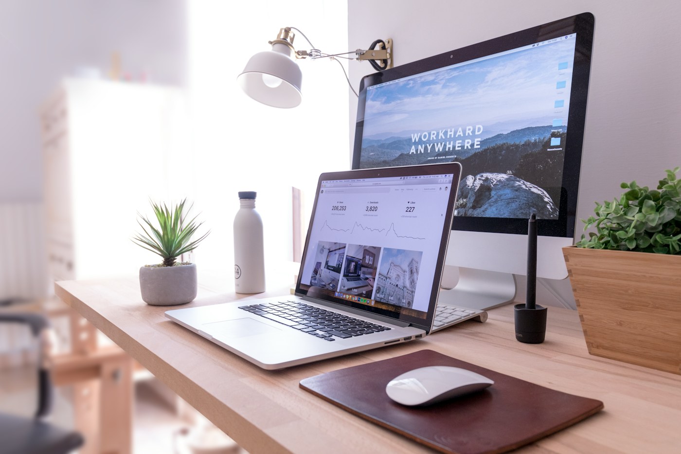 A laptop and external monitor arranged on a bright wooden desk