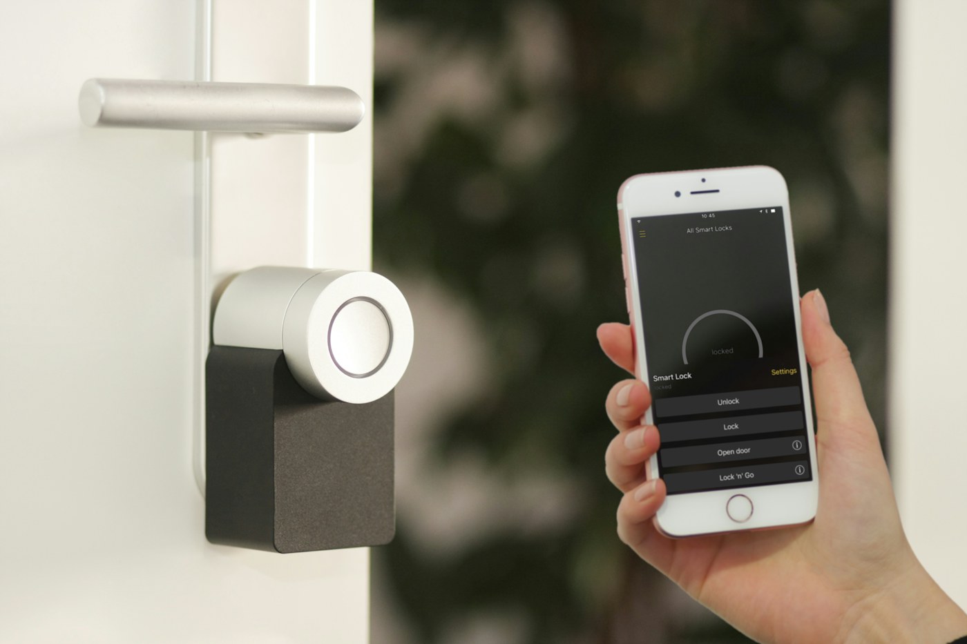 A person holding a smartphone beside a connected door lock
