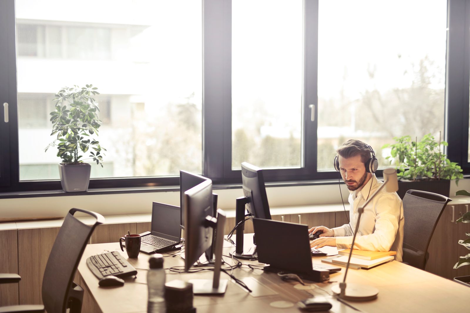 A person wearing a headset at a desk in a sunlit office